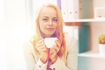 Image showing happy businesswoman drinking coffee at office