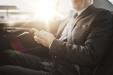 Image showing senior businessman texting on smartphone in car