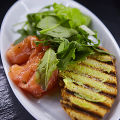 Image showing sandwich with smoked salmon, cheese, tomatoes and herbs for healthy breakfast. close up