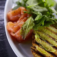 Image showing sandwich with smoked salmon, cheese, tomatoes and herbs for healthy breakfast. close up