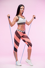 Image showing The woman training against pink studio with jump rope