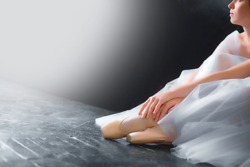 Image showing Young ballerina, closeup on legs and shoes, sitting in pointe shooses
