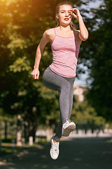 Image showing Pretty sporty woman jogging at park in sunrise light