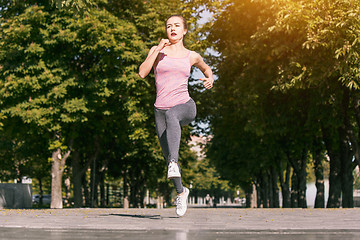 Image showing Pretty sporty woman jogging at park in sunrise light