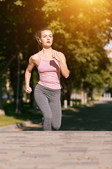 Image showing Pretty sporty woman jogging at park in sunrise light