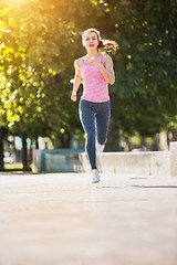 Image showing Pretty sporty woman jogging at park in sunrise light