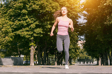 Image showing Pretty sporty woman jogging at park in sunrise light