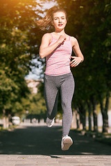 Image showing Pretty sporty woman jogging at park in sunrise light