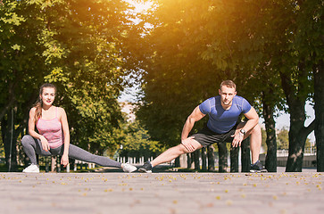 Image showing Fit fitness woman and man doing stretching exercises outdoors at park