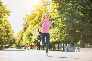 Image showing Pretty sporty woman jogging at park in sunrise light