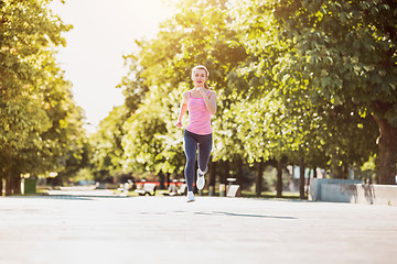 Image showing Pretty sporty woman jogging at park in sunrise light