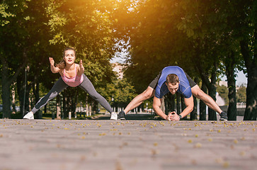 Image showing Fit fitness woman and man doing stretching exercises outdoors at park