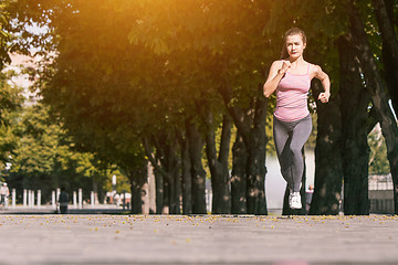 Image showing Pretty sporty woman jogging at park in sunrise light