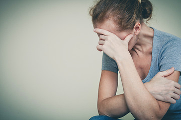 Image showing one sad woman sitting near a wall