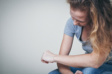 Image showing one sad woman sitting near a wall