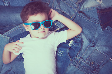 Image showing Cute little boy with sunglasses on the background jeans.