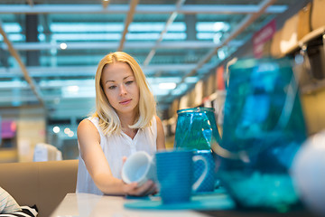 Image showing Woman choosing the right decor for her apartment in a modern home furnishings store.