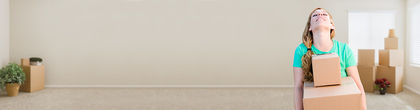 Image showing Banner of Tired Young Adult Woman Holding Moving Boxes In Empty 