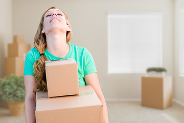 Image showing Tired Young Adult Woman Holding Moving Boxes In Empty Room In A 