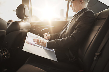 Image showing senior businessman with papers driving in car