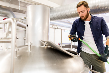 Image showing man with hose working at craft beer brewery kettle