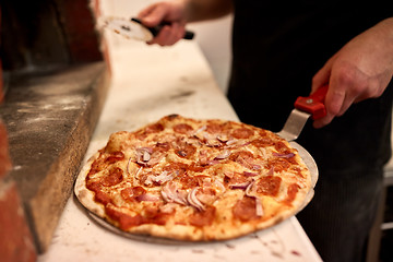 Image showing cook with pizza peel and cutter at pizzeria