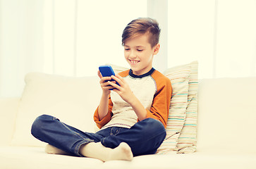 Image showing boy with smartphone texting or playing at home