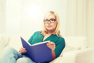 Image showing young woman in glasses reading book at home