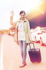 Image showing smiling young woman with travel bag over taxi