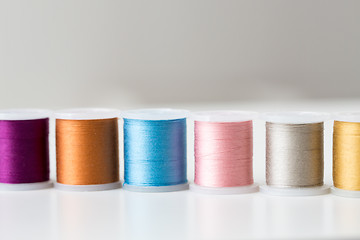 Image showing row of colorful thread spools on table