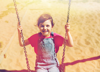 Image showing happy little girl swinging on swing at playground