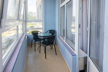 Image showing A table and three chairs on the balcony in the apartment of a multistory apartment building