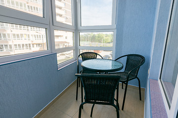 Image showing A table and three chairs on the balcony in the apartment of a multistory apartment building