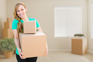 Image showing Happy Young Adult Woman Holding Moving Boxes In Empty Room In A 