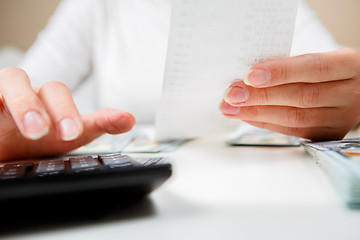 Image showing savings, finances, economy and home concept - close up of hands with calculator counting money and making notes at home