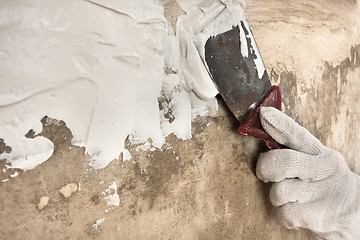 Image showing hand in glove plastering concrete wall with spatula