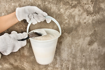 Image showing hands holding bucket with plaster and spatula