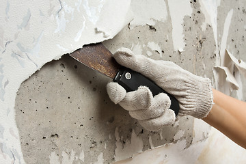 Image showing hand removing wallpaper from wall with spatula