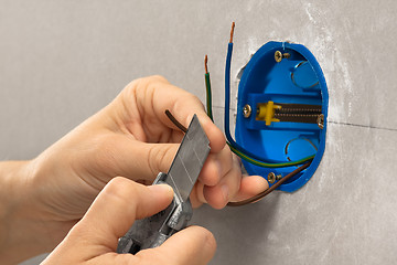 Image showing hands of electrician striping the insulation of wires