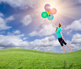 Image showing Young Girl Being Carried Up and Away By Balloons That She Is Hol