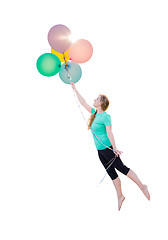 Image showing Young Girl Being Carried Up and Away By Balloons That She Is Hol