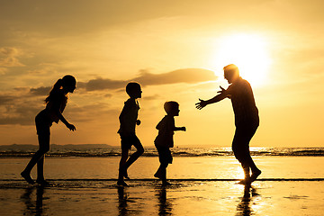 Image showing Father and children playing on the beach at the sunset time.