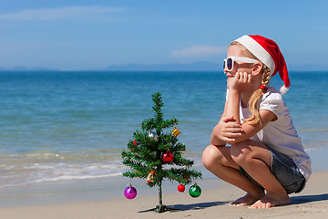 Image showing Happy little girl sitting on the beach at the day time.