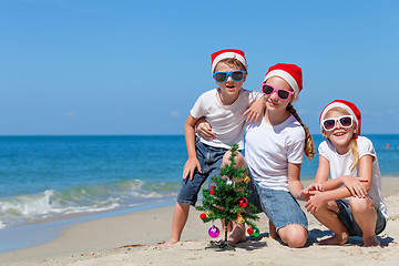 Image showing Three happy children  playing on the beach at the day time. 