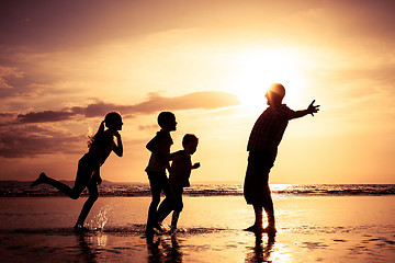 Image showing Father and children playing on the beach at the sunset time.