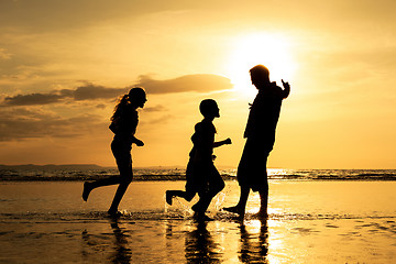 Image showing Father and children playing on the beach at the sunset time.