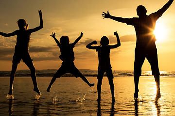 Image showing Father and children playing on the beach at the sunset time.