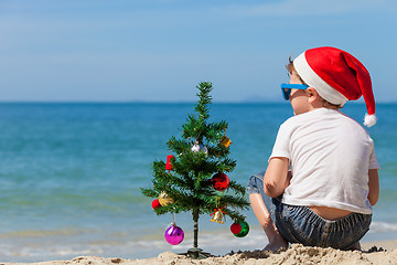 Image showing Happy little boy sitting on the beach at the day time. 