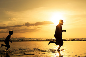 Image showing Father and son playing on the beach at the sunset time.