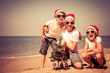 Image showing Three happy children  playing on the beach at the day time.